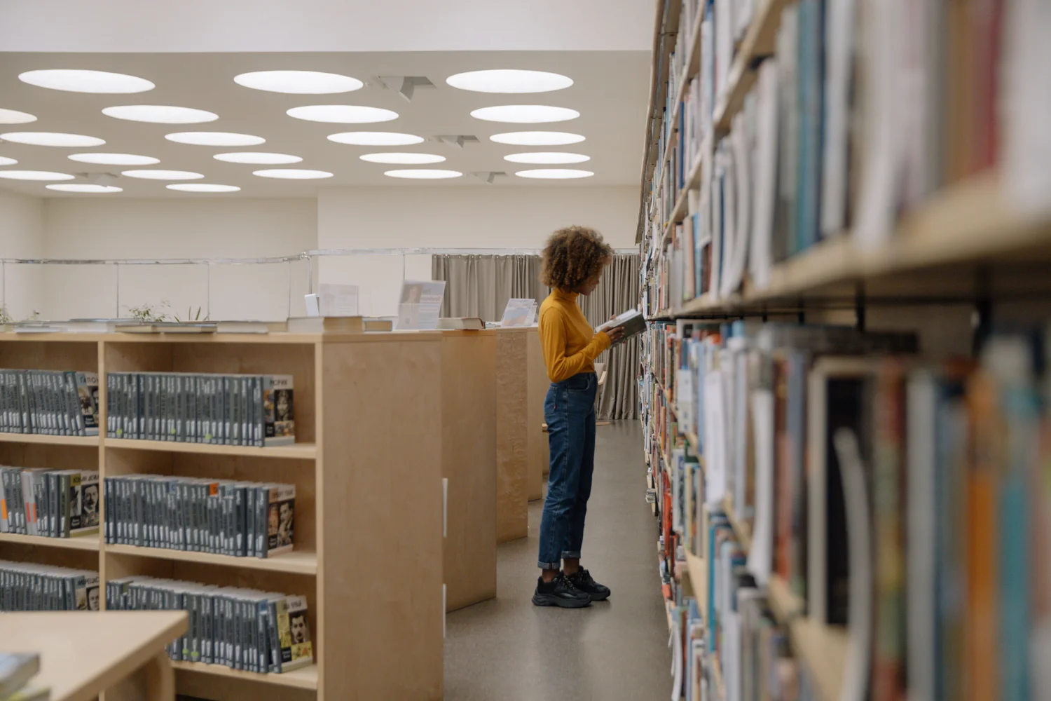 A woman reading a book in a library. · Illustrative stock photo