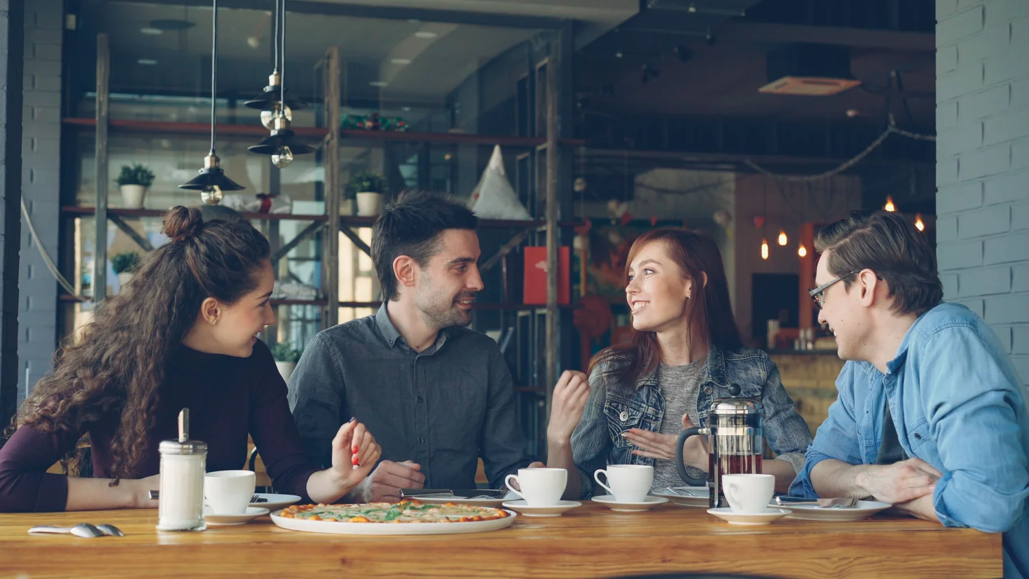 Friends sharing a conversation over coffee in a café. · Illustrative stock photo
