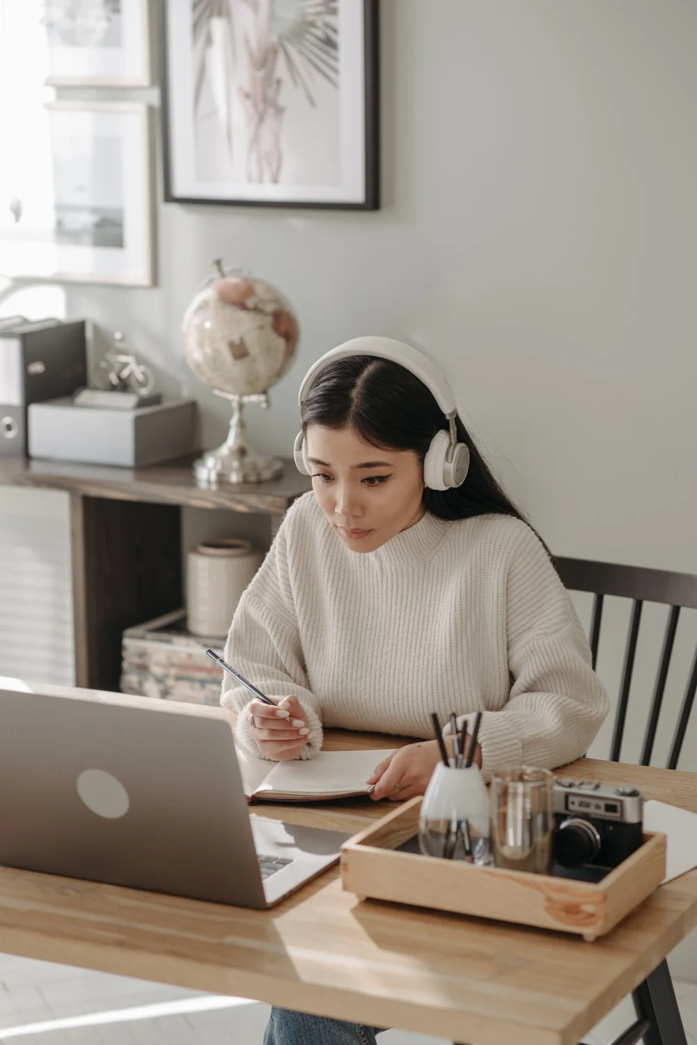 An adult learner studying with headphones, a laptop and notes. · Illustrative stock photo