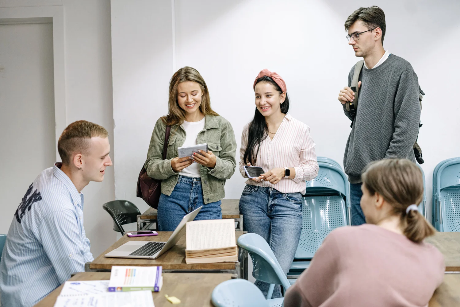 Young adults discussing study materials around a classroom table. · Illustrative stock photo