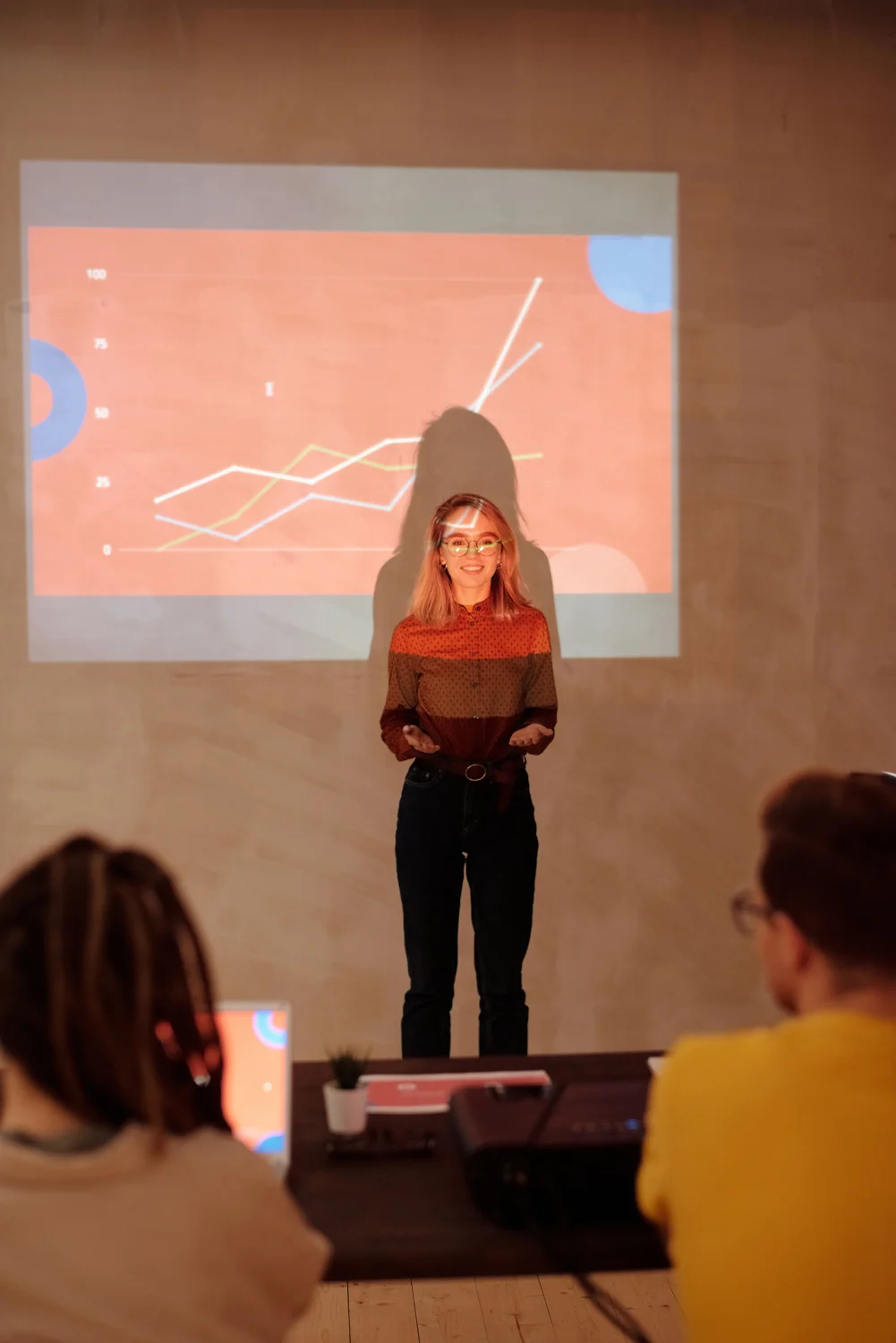 A professional presenting a projected graph during a meeting. · Illustrative stock photo
