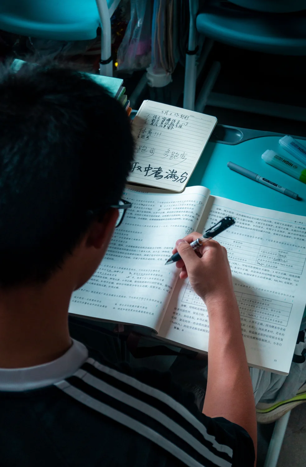 A teenager studying with open books and notes at a desk. · Illustrative stock photo